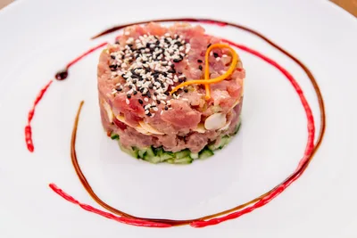 Fresh tuna tartare made with sushi-grade tuna, avocado, cucumber, sesame seeds, and microgreens.