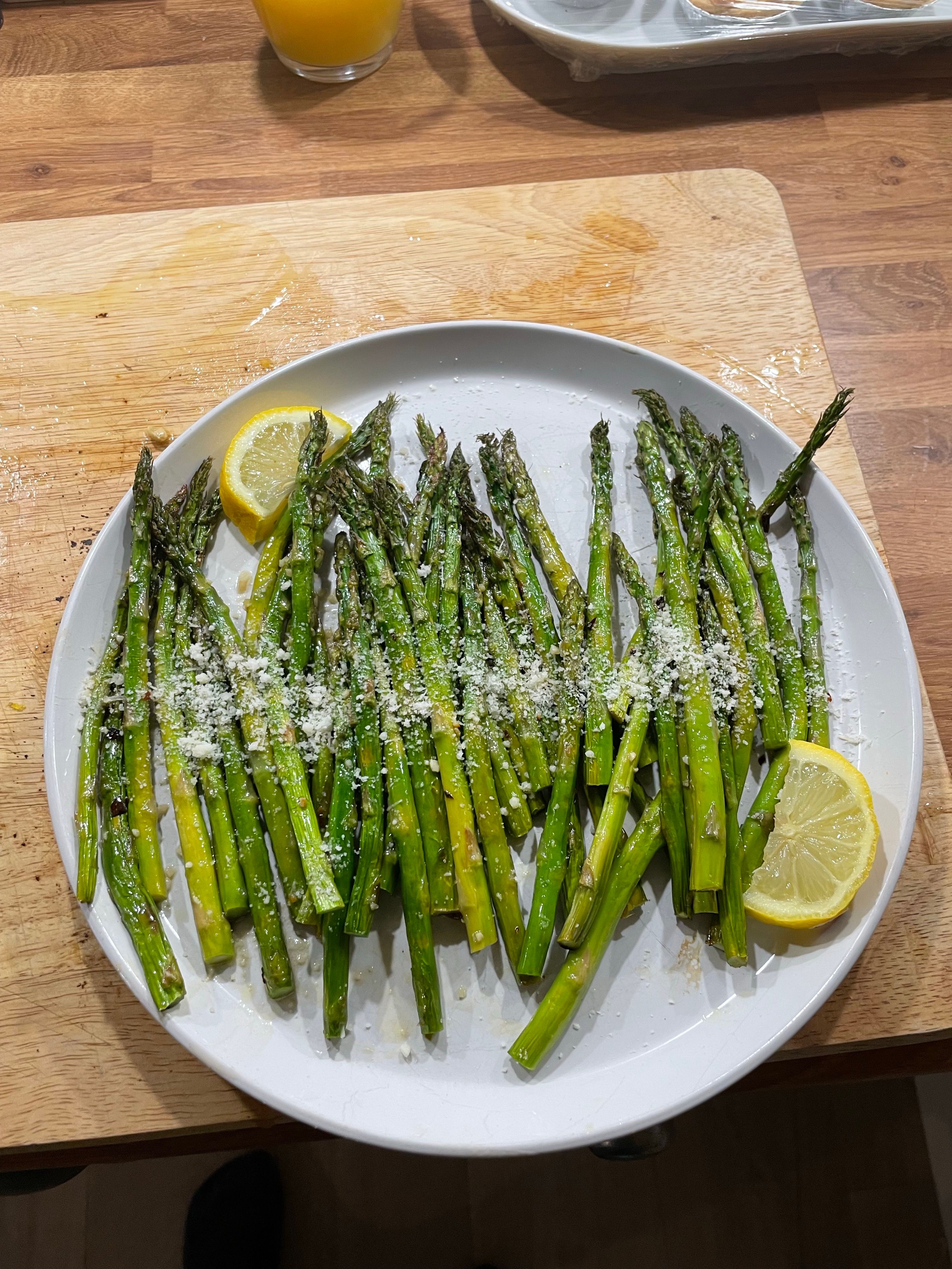 Roasted asparagus with lemon, garlic and grated Parmesan on a serving plate.