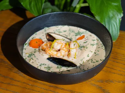 Creamy fish chowder with chunks of cod, salmon, potatoes, corn and fresh herbs in a white soup bowl.