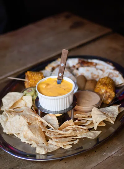 Creamy Mexican white cheese dip with green chiles and jalapeño served in a bowl surrounded by tortilla chips.