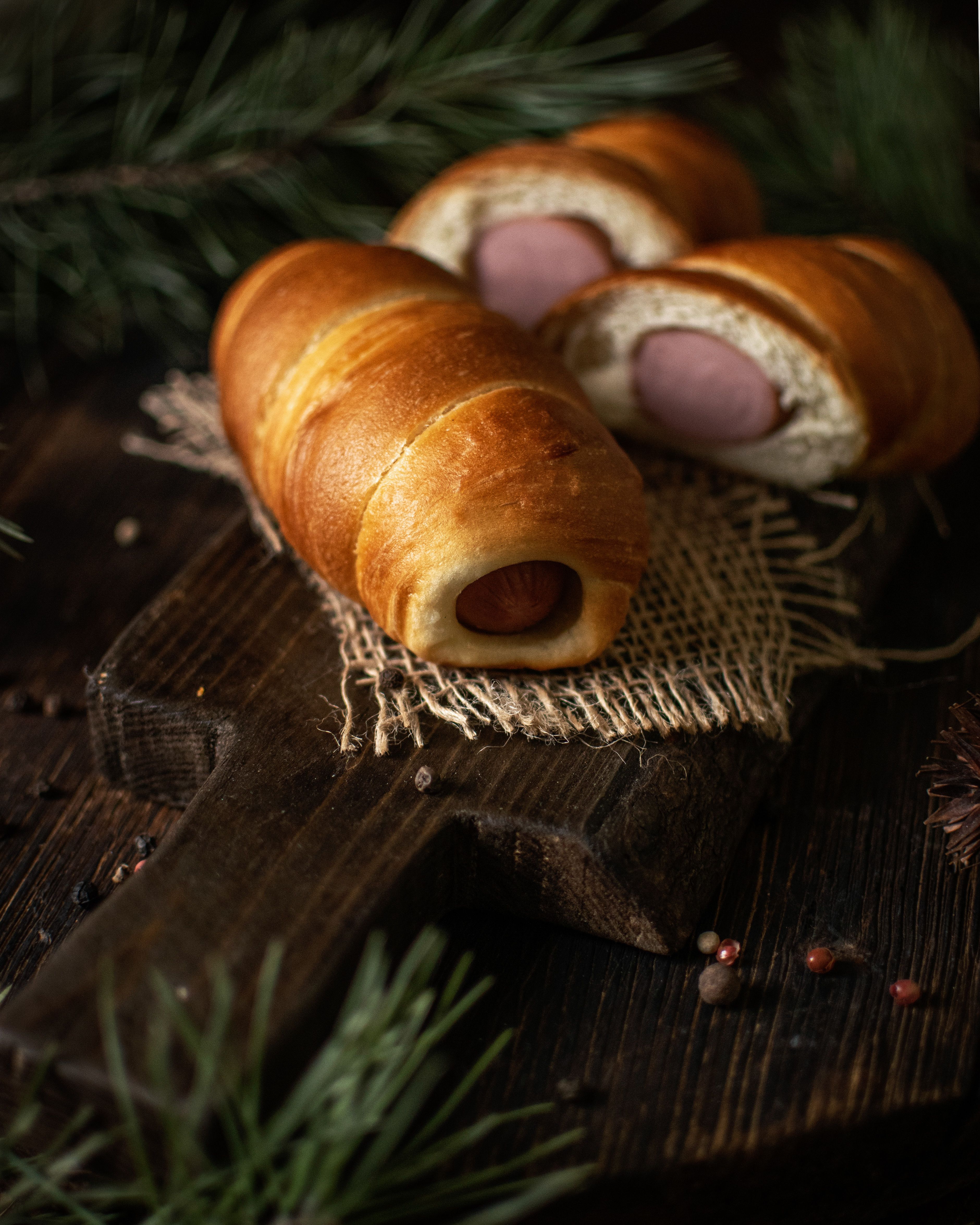 Golden homemade sausage rolls filled with seasoned pork and arranged on a serving board with tomato sauce.