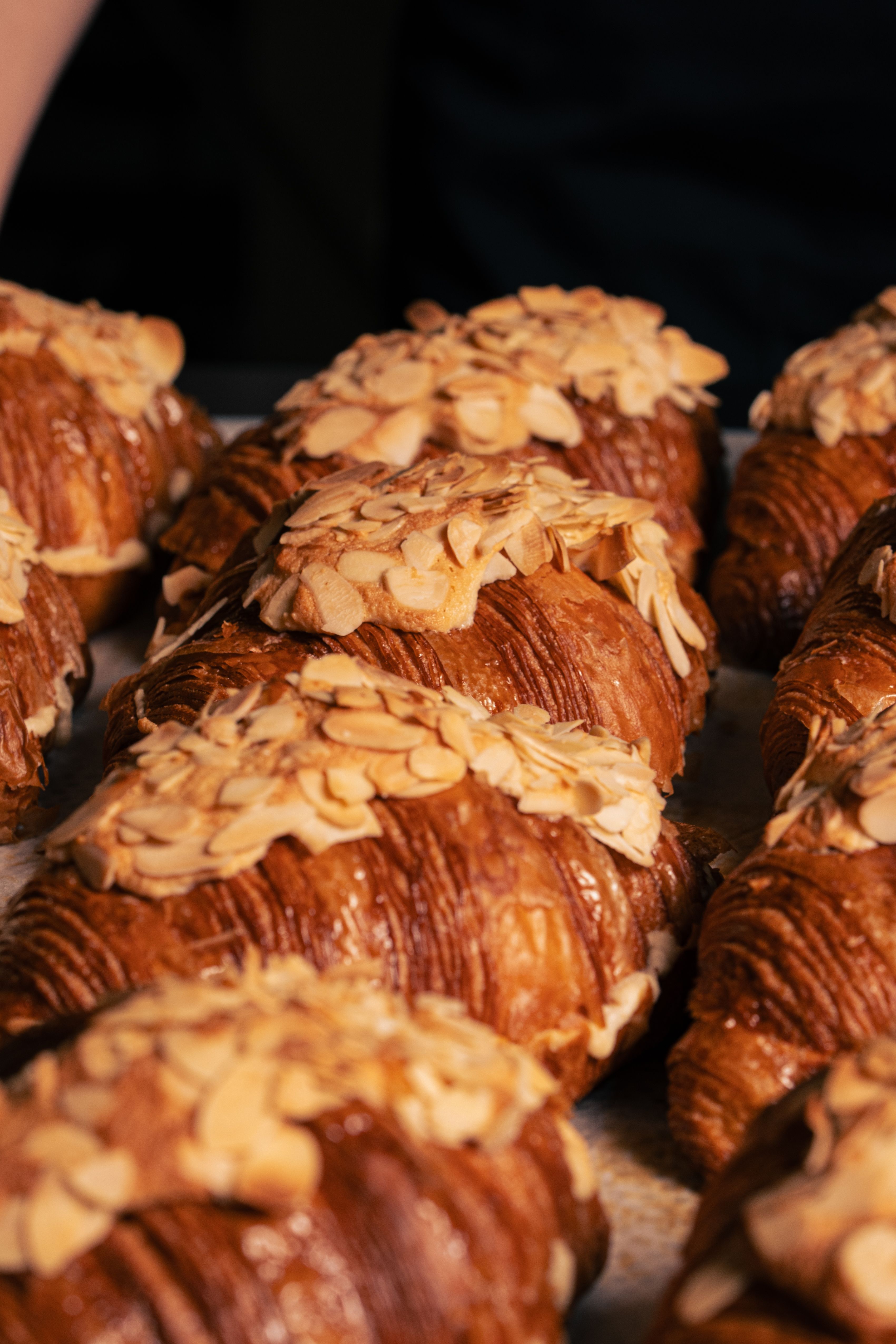Freshly baked almond croissants filled with almond cream and topped with toasted sliced almonds and powdered sugar.