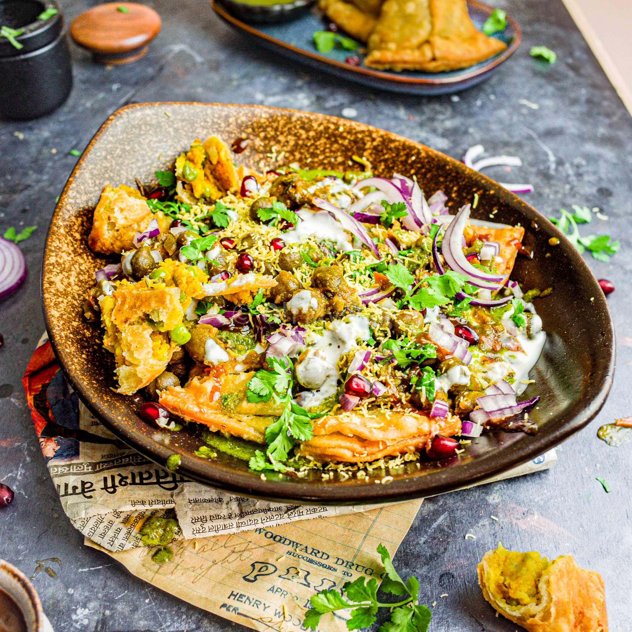 Crushed samosas topped with yogurt, chutneys, and spices