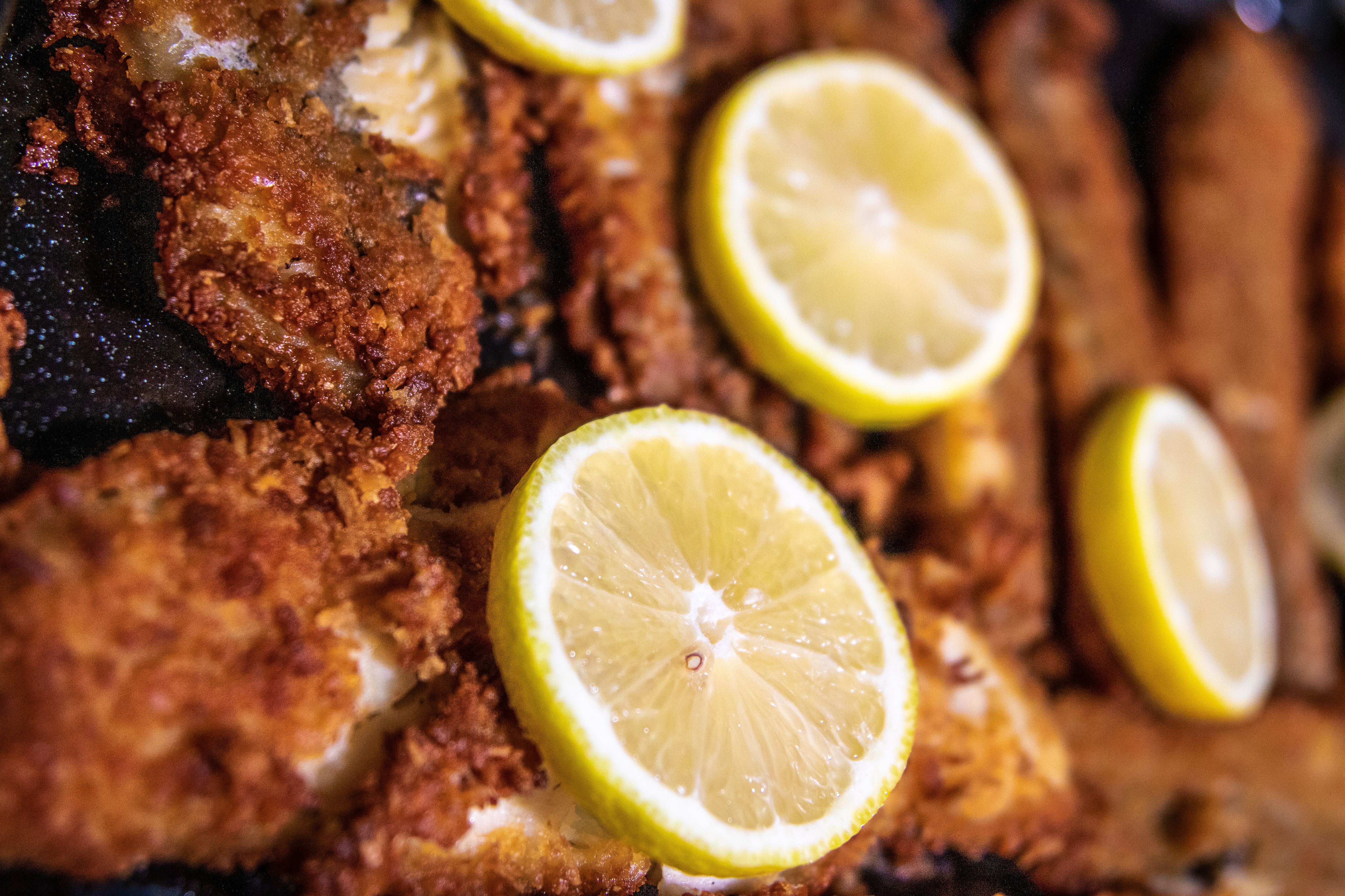 Crispy golden beer-battered white fish pieces served on a wire rack with fresh lemon wedges.