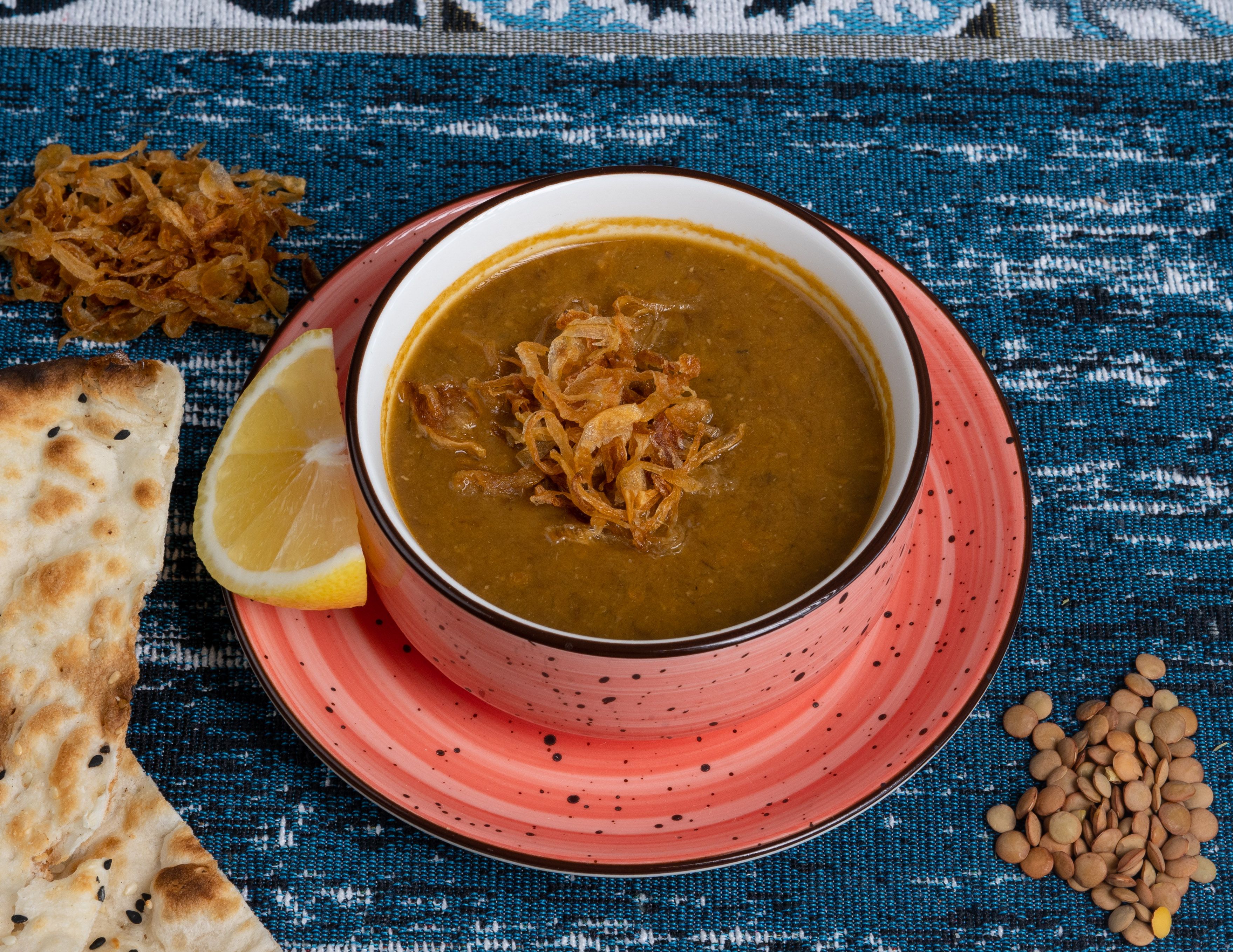 Pakistani beef haleem topped with fried onions, ginger, coriander, green chilies, lemon, and hot ghee