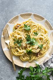 A close up of glossy miso carbonara topped with cracked black pepper and chives