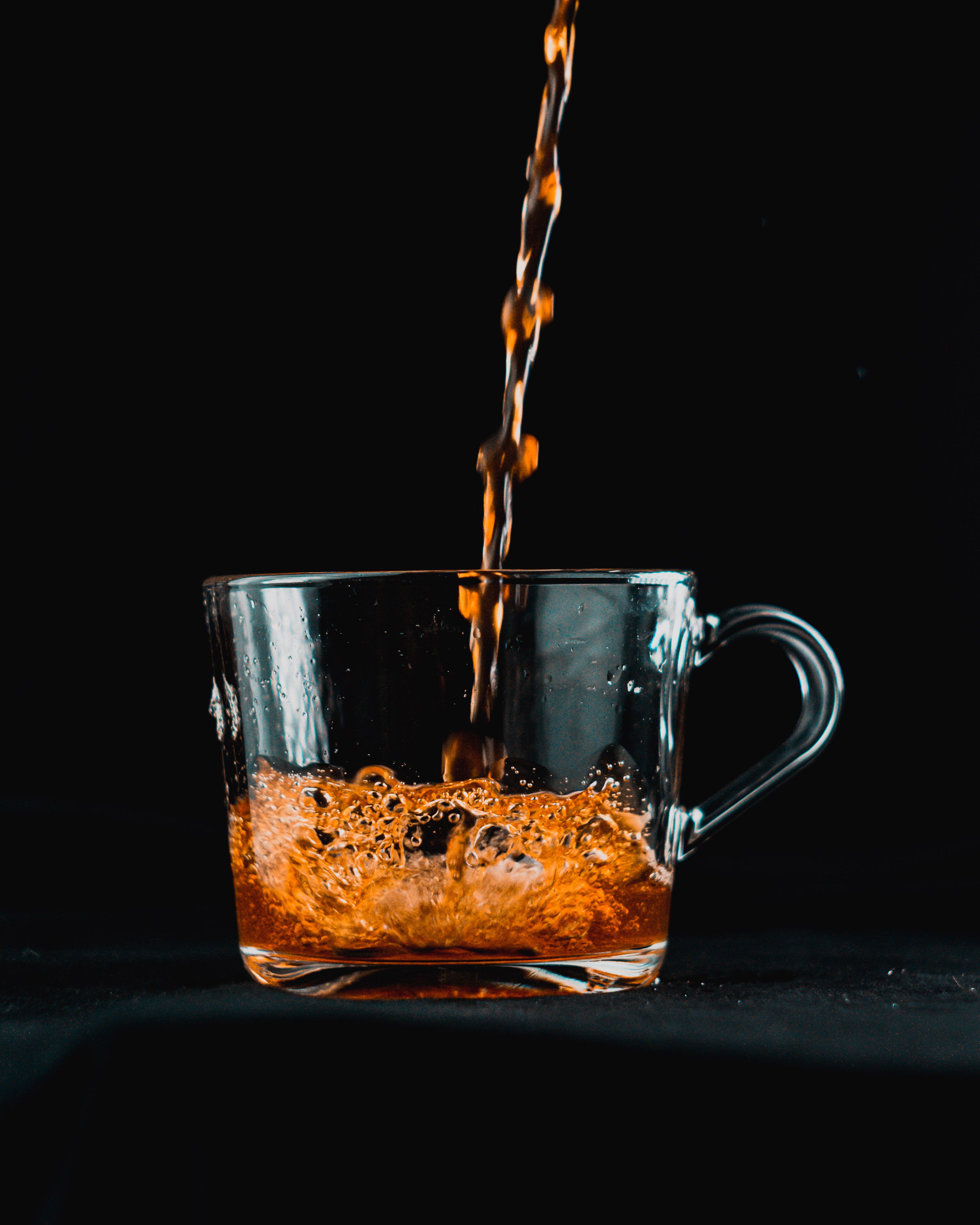 Black tea in a clear cup beside a caffeine comparison chart showing milligrams by serving size