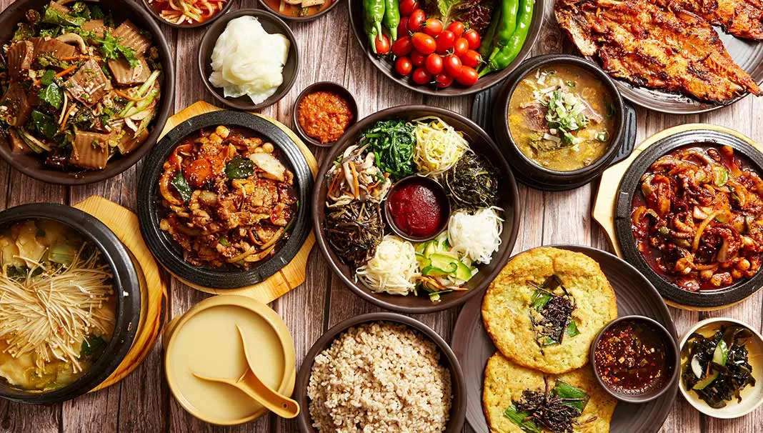 A Korean cuisine cookbook cover featuring spicy mains, pancakes, kimchi dishes, noodles, and popular street food.