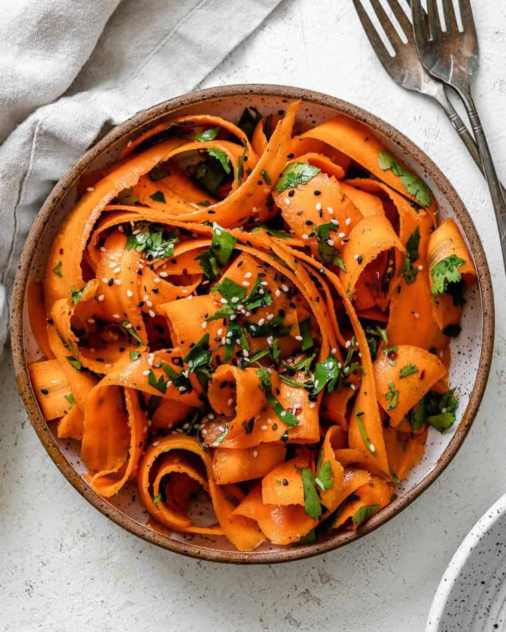 Fresh shredded carrot salad with lemon dressing and herbs.