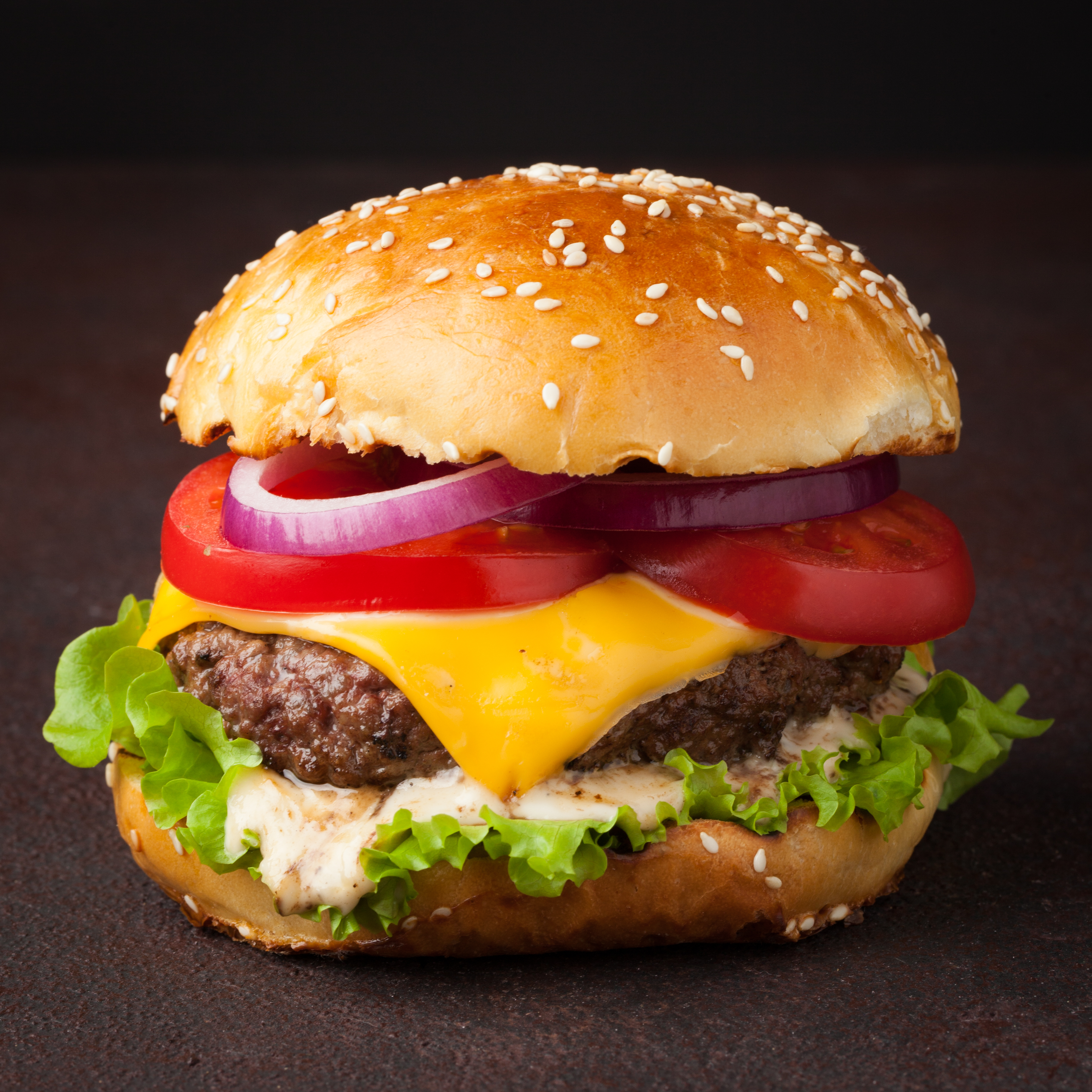 A Krabby Patty-inspired cheeseburger with lettuce, tomato, onion, pickles, and tangy sauce in a sesame bun.