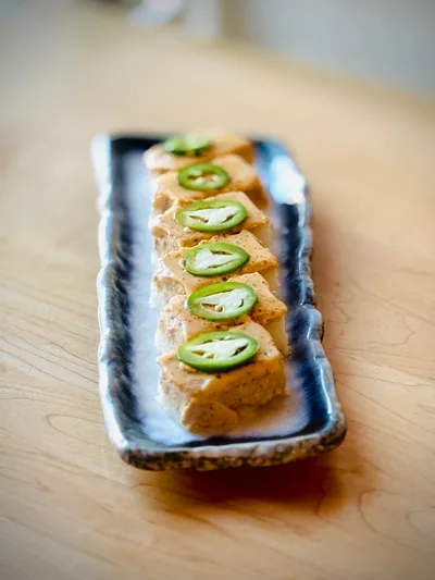 Golden crispy agedashi tofu cubes in a shallow bowl of dashi sauce topped with grated daikon, ginger, and scallions.