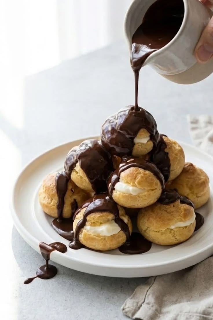 Profiteroles filled with vanilla ice cream and topped with chocolate sauce.