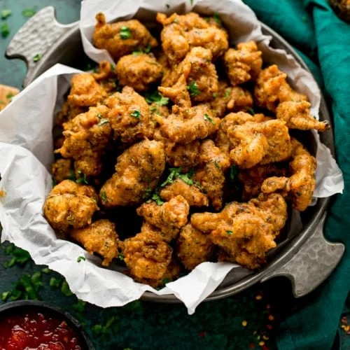 Golden chicken pakoras served hot with a crunchy gram flour coating and dipping sauce.