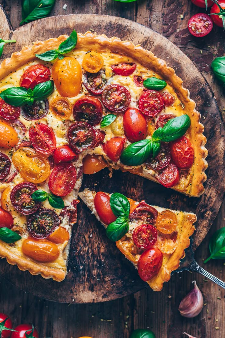 Golden puff pastry tomato tart topped with herbs and Parmesan cheese.