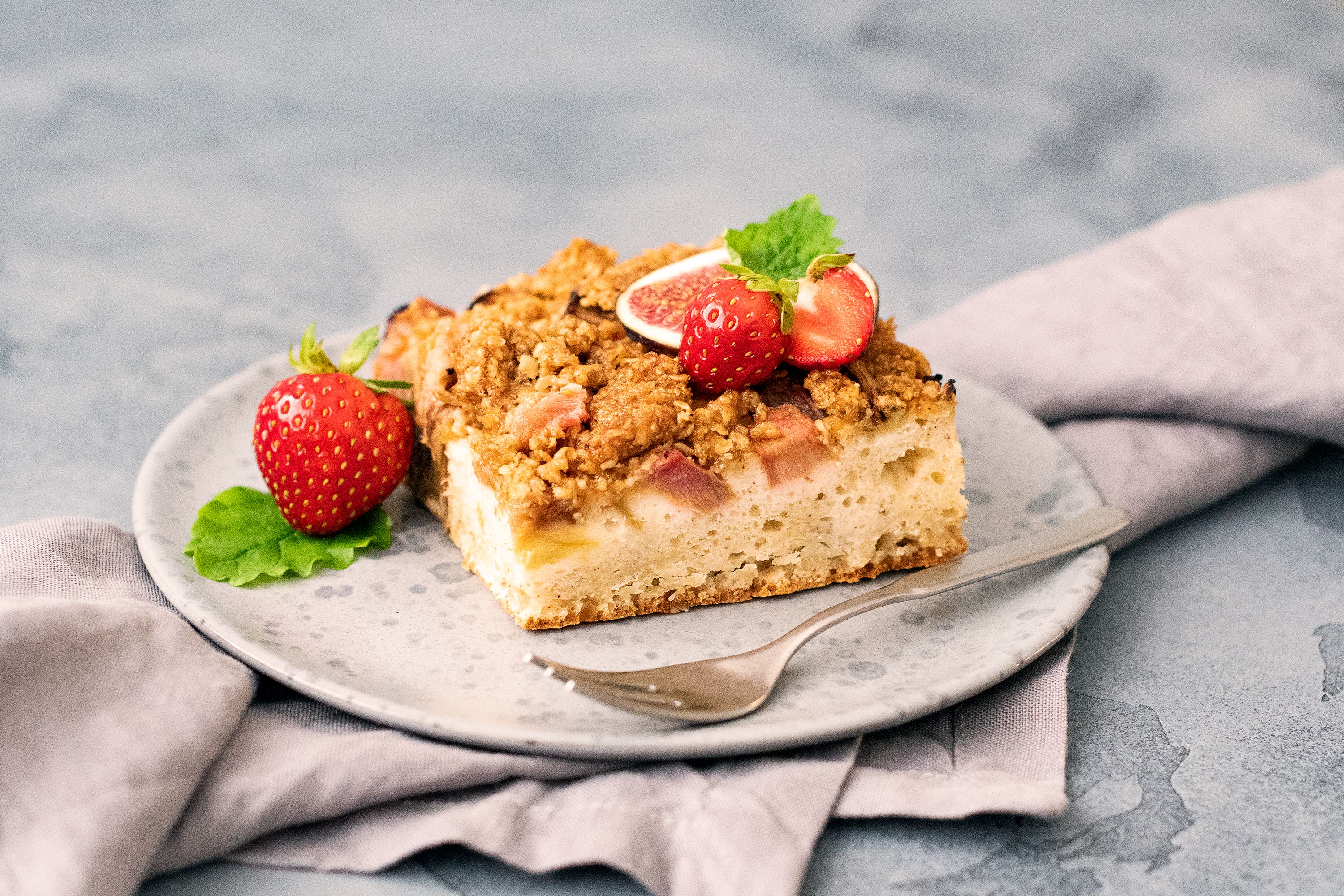 Warm strawberry rhubarb crisp with a golden brown oat topping served in a bowl with vanilla ice cream.