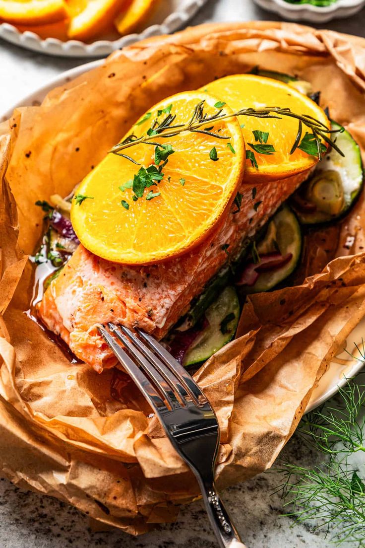 Salmon baked in parchment with orange slices and broccoli.