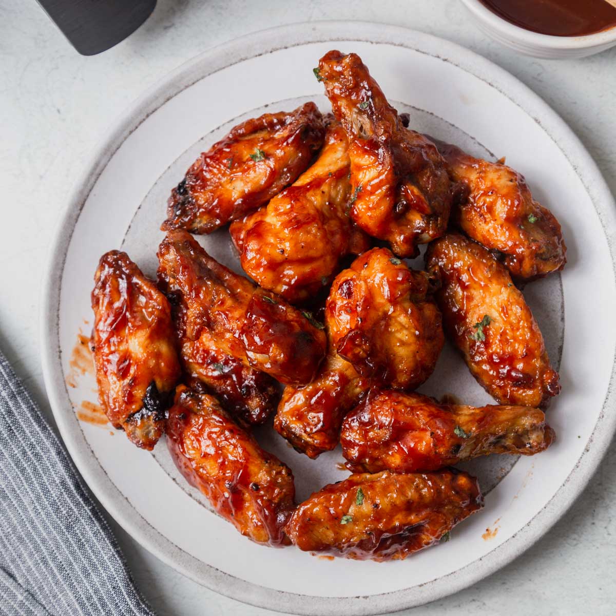 A platter of smoky BBQ chicken wings glazed with butter and served hot with dipping sauce.
