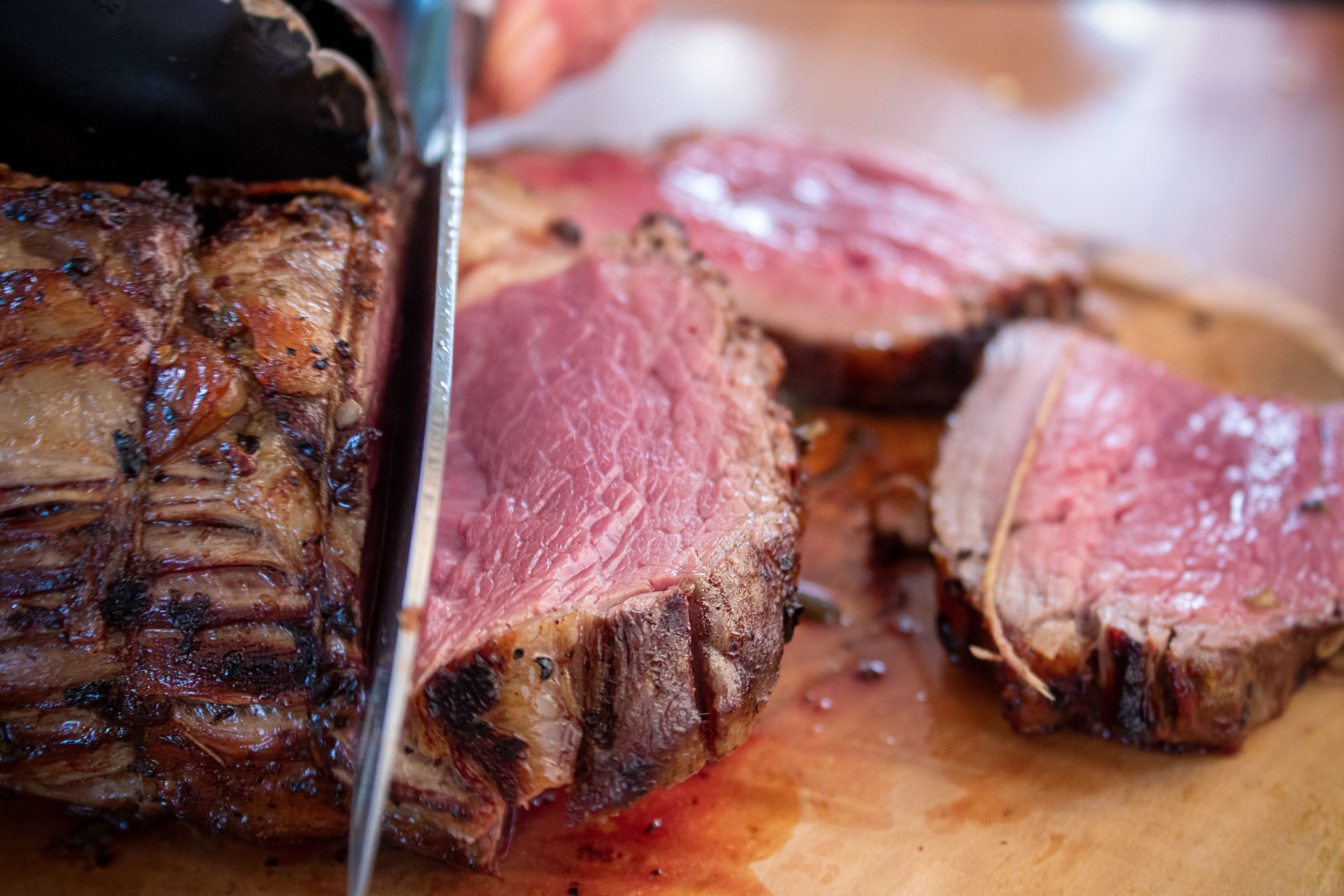 Garlic herb ribeye roast sliced to reveal a juicy centre and served with rich red wine pan jus.