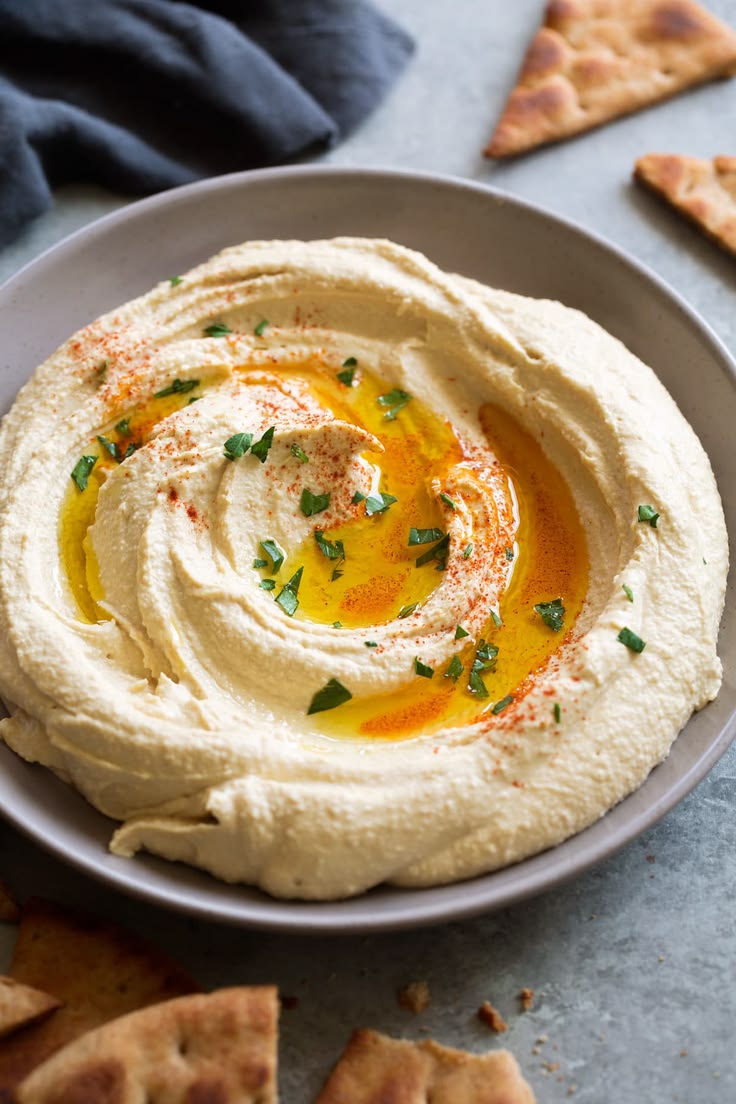 Creamy hummus served with olive oil, paprika, and olives.