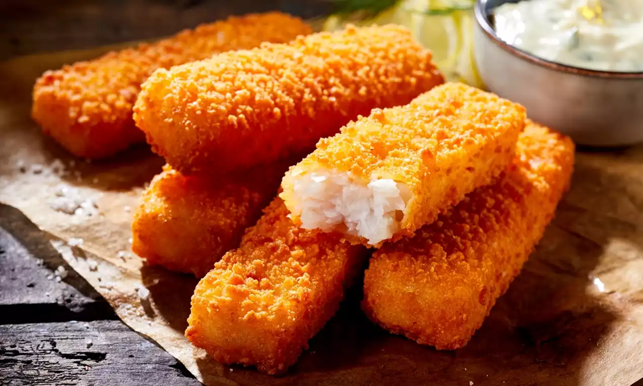 Golden crispy fish fingers served with a dipping sauce on the side.
