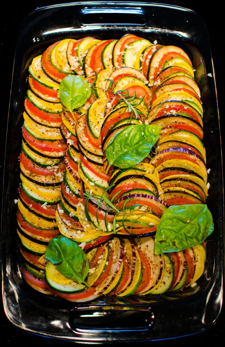 Confit byaldi layered vegetables baked in tomato pepper sauce arranged in spiral pattern.